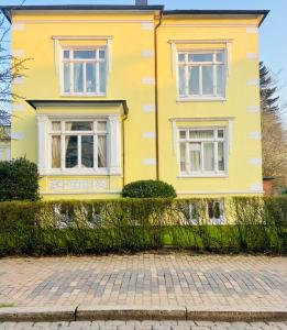 a yellow house with white windows and a brick driveway at Ankerplatz Neumünster, Parkplatz in Neumünster