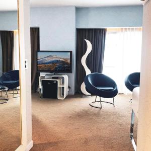 a living room with chairs and a tv and a television at Virgo Hotel & Spa in Las Lenas