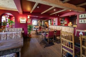 ein Restaurant mit roten Wänden, einem Tisch und Stühlen in der Unterkunft The White Hart, Wroughton in Swindon