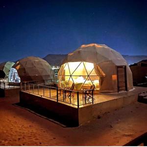 two domes in the desert lit up at night at Madar Camp, Wadi Rum in Wadi Rum