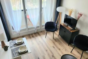 a living room with a television and a table and chairs at Beautiful apartment with 3 balconies in Blonville-sur-Mer