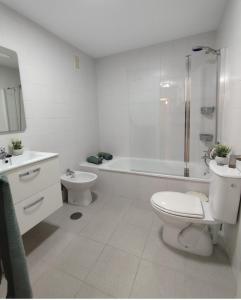 a white bathroom with a toilet and a tub and a sink at Habitacion Familiar LOVELY SEVILLA con baño compartido in Camas