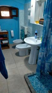 a blue bathroom with two toilets and a sink at La casa di Lilith in Sennori