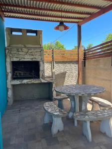 a patio with a table and benches and a fireplace at casa de un ambiente in Funes
