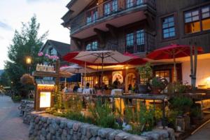 a restaurant with tables and umbrellas in front of a building at Sunny Vail Mountainside Getaway Amazing Location in Vail