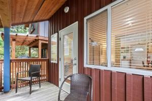 eine Veranda mit 2 Stühlen, einem Tisch und einem Fenster in der Unterkunft Tyee Retreat Cozy Lofted 1 Bedroom Cabin in Ucluelet