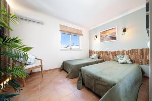 a room with two beds and a plant at Casa Paraiso - stylish gateway in Carvoeiro