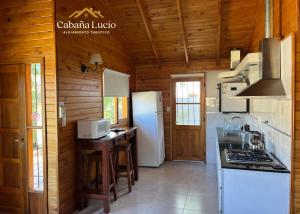 a kitchen with wooden walls and a white refrigerator at Cabaña Lucio in Esquel