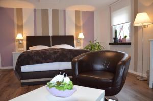 ein Hotelzimmer mit einem Bett und einem Ledersessel in der Unterkunft Gästehaus Praliné in Bremm
