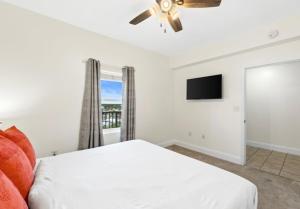 a bedroom with a white bed and a flat screen tv at BeachFrnt 2 Hottub 5 Pools Jet Ski in Panama City Beach