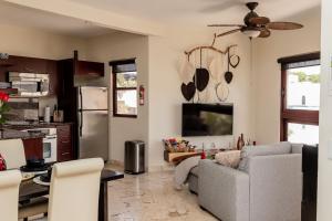 cocina y sala de estar con sofá y TV en Beachfront Chic at El Faro Resort, en Playa del Carmen