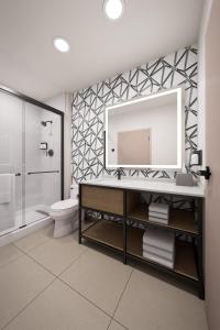 a bathroom with a sink and a toilet and a mirror at Atwell Suites Corpus Christi Southeast by IHG in Corpus Christi