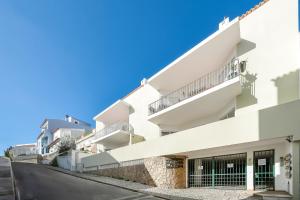 a white building with balconies on a street at Casa Paraiso - stylish gateway in Carvoeiro