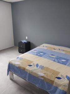 a bedroom with a bed with a blue and tan quilt at Family Cutting House in Xalostoc +7 photos