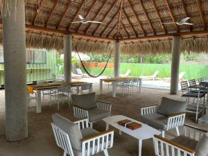 a patio with tables and chairs and a hammock at Marena Surf Shack - Casa Akaw in La Salada