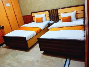 2 bedden met oranje en witte lakens in een kamer bij Karachi Motel Guest House in Karachi
