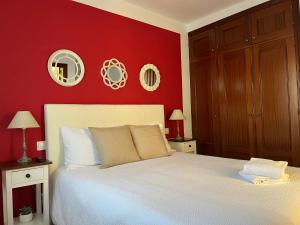 a bedroom with a white bed with a red wall at Margarita House in Arrecife