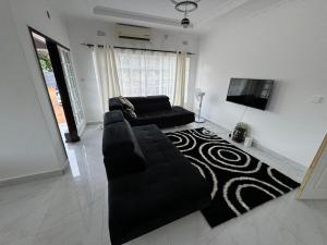 uma sala de estar com um sofá preto e uma televisão de ecrã plano em Yeta Apartments em Livingstone