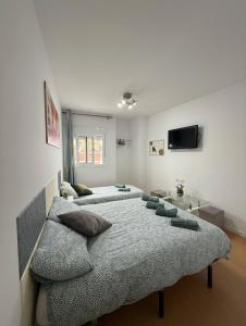 una camera da letto con due letti e una TV a schermo piatto di HABITACIÓN triple con baño compartido LOVELY SEVILLA a Camas