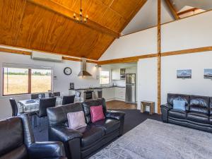 a living room with leather furniture and a kitchen at Willstone Chalet - Ohakune Chalet near Turoa in Ohakune