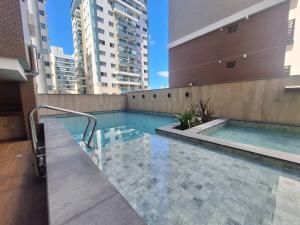 a swimming pool on top of a building with tall buildings at Apartamento luxo, pertinho do Mar e lazer maravilhoso in Vila Velha
