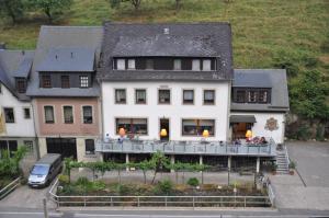 une grande maison blanche avec des personnes assises sur un balcon dans l'établissement Gutsschänke Sennerhof, à Oberwesel