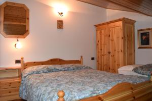アラッバにあるAppartamento Sellarondaのベッドルーム1室(木製ベッド1台、木製キャビネット付)
