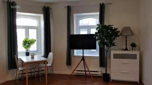 Una sala de estar con un televisor y una mesa y dos ventanas. en Cozy Suite #3 in the Heart of DT Quebec with QB, en Quebec