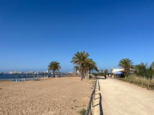 a sandy beach with palm trees and the ocean at Fantástico Ático Chill Out con Vistas a Mar de Cristal in Mar de Cristal