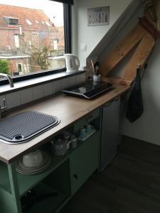 eine Küche mit einer Theke mit einem Waschbecken und einem Fenster in der Unterkunft De Weegbrug in IJzendijke