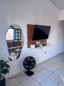 a room with a tv and a chair and a mirror at Primos Hostel & House in Búzios
