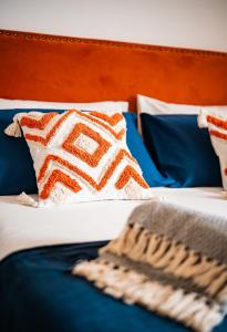 1 cama con almohadas azules y naranjas y almohada marrón y blanca en Il gabbiano, en Otranto