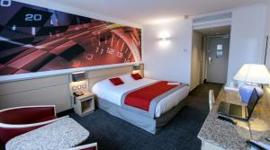 a hotel room with a bed and a tv at Hotel Le Paddock in Magny-Cours