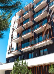an apartment building with balconies and trees at La Onda Hotel Durres in Durrës