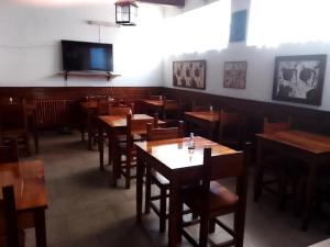a restaurant with wooden tables and a flat screen tv at Hotel Medina y Mar BnB in Mar del Plata