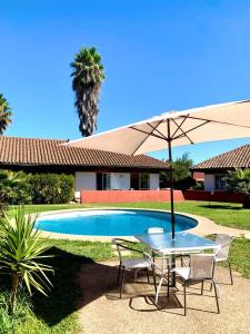 a table and chairs with an umbrella next to a pool at Apart hotel Entre Ríos ruta 5 Talca in Talca