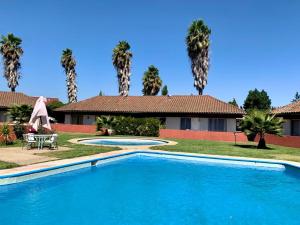 a swimming pool in front of a house with palm trees at Apart hotel Entre Ríos ruta 5 Talca in Talca