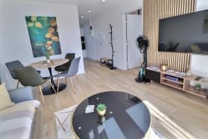 a living room with a table and a tv at Appartement Moderne et Cosy avec Balcon - Parking Gratuit - Netflix in Logelbach