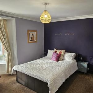 a bedroom with a large bed with a purple wall at Snuze Whitby in Whitby +34 photos
