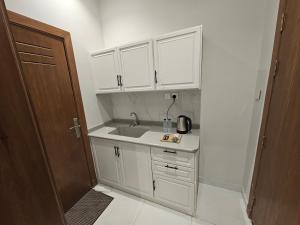 a kitchen with white cabinets and a sink at سكينة المدينة 101 in Al Madinah