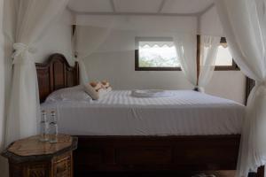 a bedroom with a large white bed with a window at Cabaña Jaguar in Flores