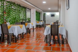 a restaurant with tables and chairs on a red brick floor at Hotel Avenida 3 Real en el norte de Cali in Cali
