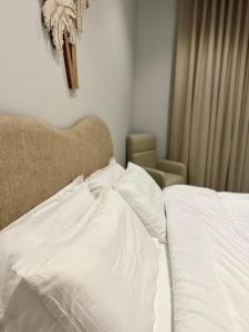 a bed with white sheets and a cross on the wall at سكينة المدينة 101 in Al Madinah