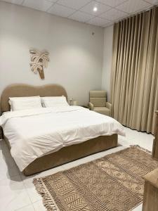a bedroom with a large white bed and a rug at سكينة المدينة 101 in Al Madinah