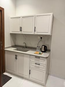 a kitchen with white cabinets and a sink at سكينة المدينة 101 in Al Madinah +4 photos