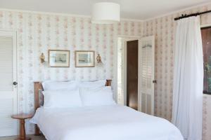 a bedroom with a white bed with pink wallpaper at Daisy Harbour View - Waterfront! in Raglan