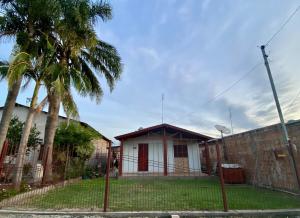 a house behind a fence with a palm tree at Casa completa para pernoite in Pântano Grande