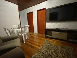 a living room with a tv and a table with chairs at Casa completa para pernoite in Pântano Grande