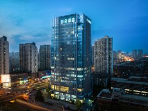 a tall glass building in a city at night at Atour Hotel Hefei Yaohai Heping Road in Hefei
