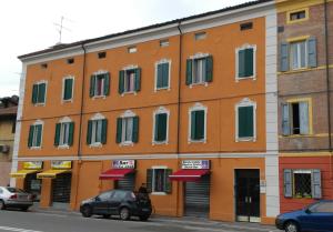 un edificio naranja con ventanas verdes en una calle en La Casa del Viandante, en Módena